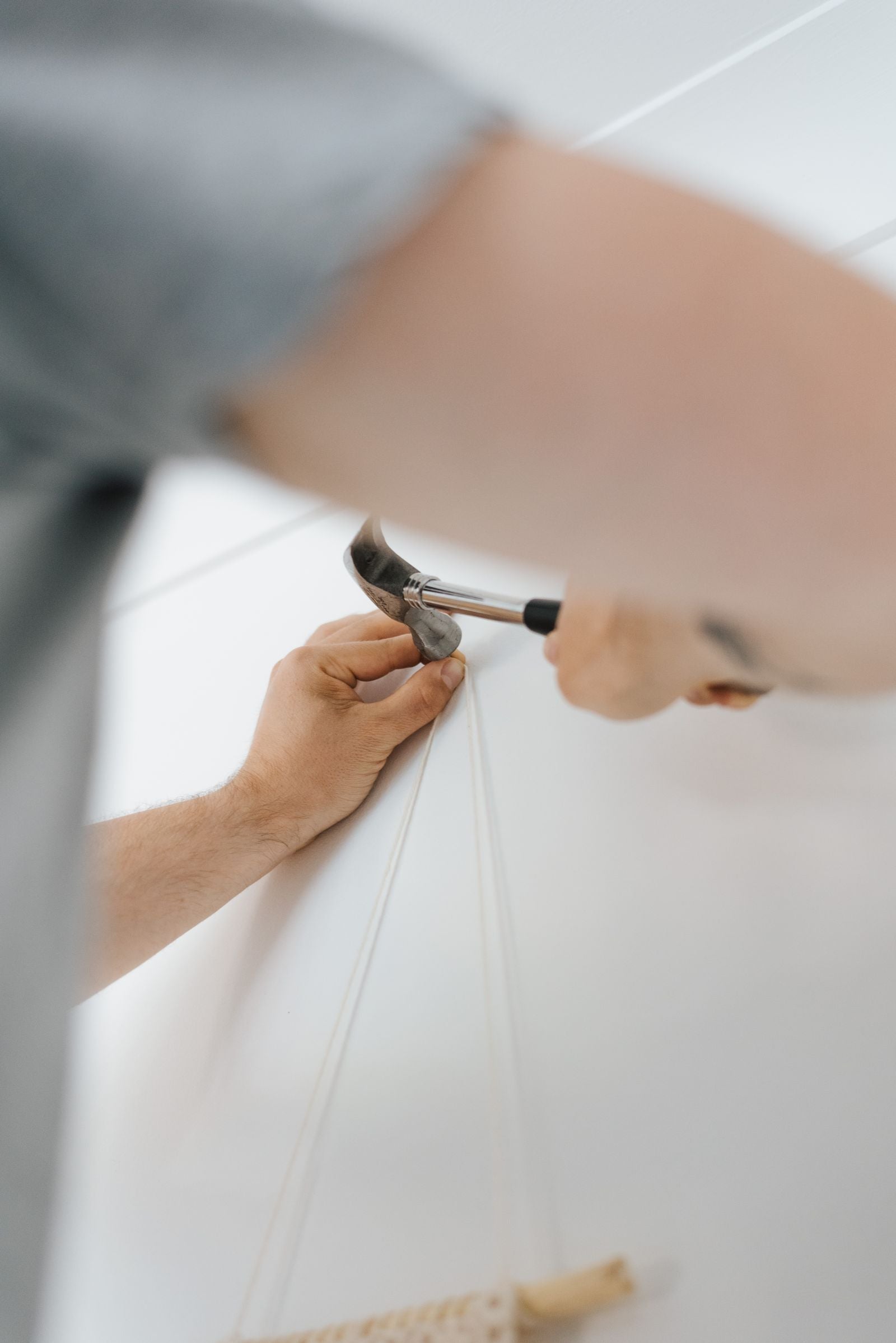 Main tenant un marteau pour fixer une décoration sur un mur