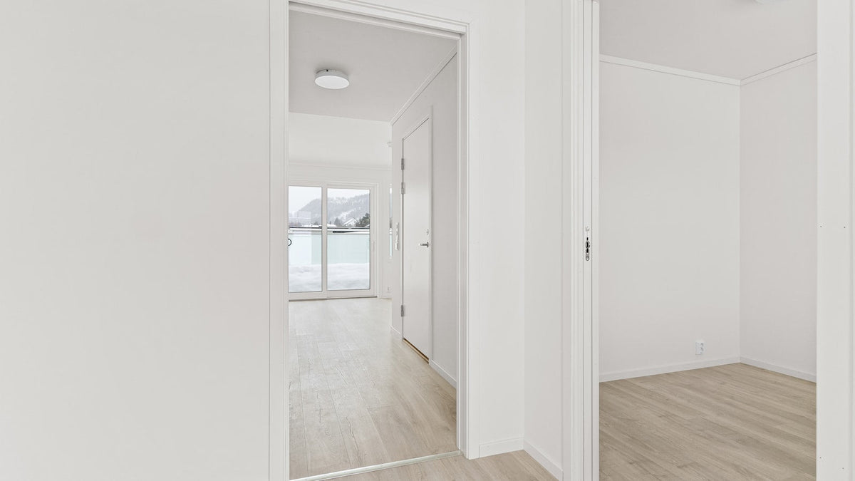 Pièce vide d'un appartement neuf, murs blancs et parquet en bois