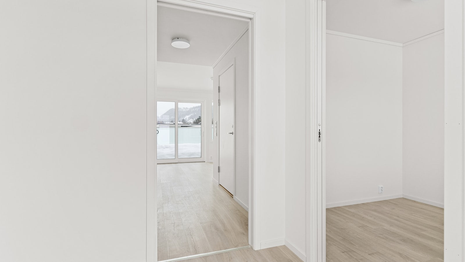 Pièce vide d'un appartement neuf, murs blancs et parquet en bois